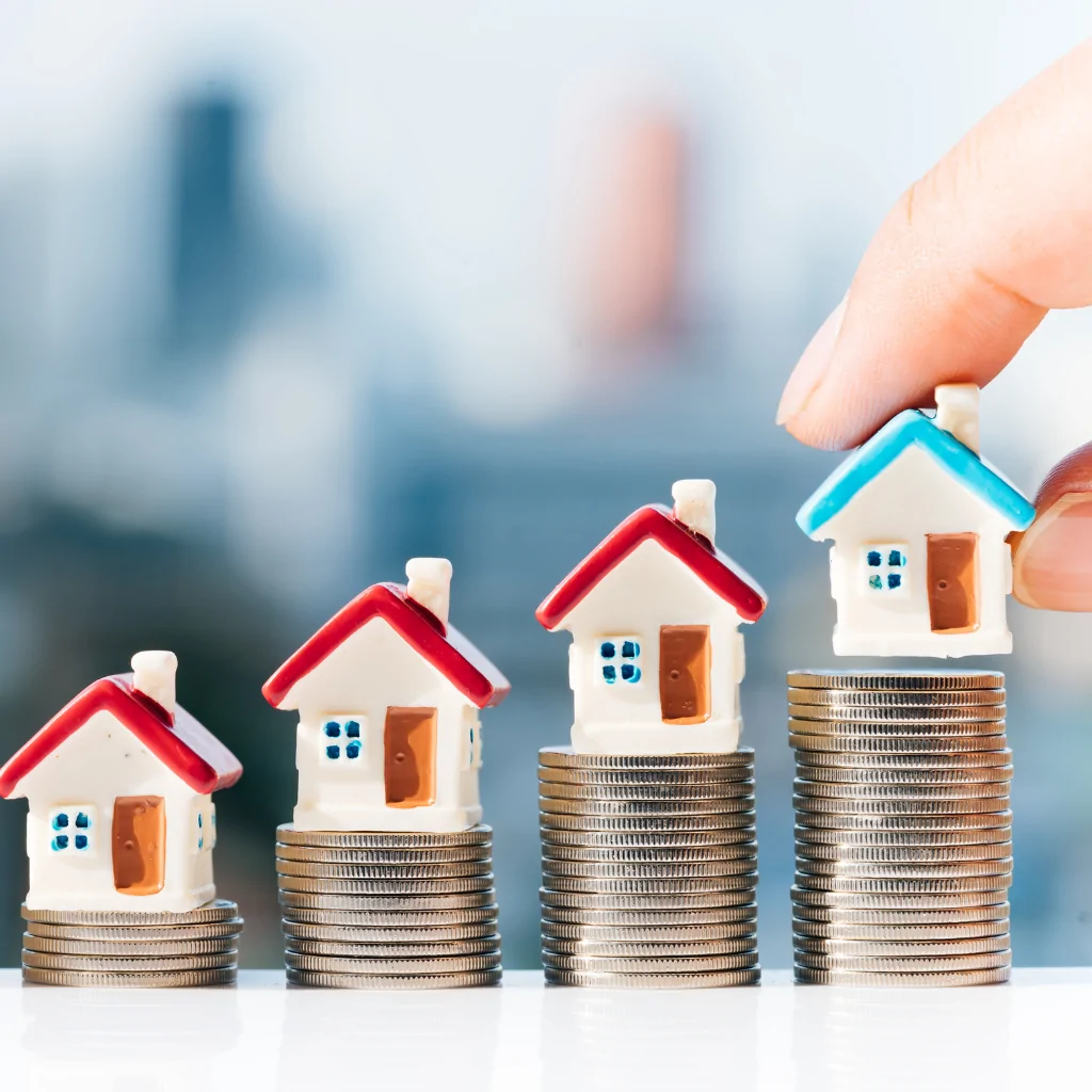 Small house models placed on stacks of coins increasing in height